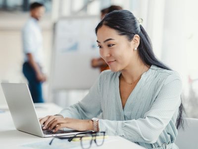 A Person Sitting At A Table Using A Laptop